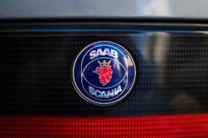 Blått Saab-Scania-emblem med rött krönt griphuvud på bakpartiet av en Saab